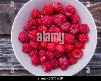 Closeup of bowl of fresh and ripe rasberries on wooden table. natural food.Ripe tasty berries.Natural vitamins. organic summer fruits. Stock Photo