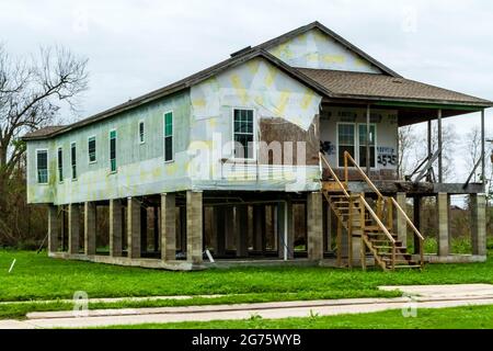 A damaged house in the Lower 9th Ward of New Orleans.  Siding is missing, porch and windows damaged, some repair has been done. Stock Photo