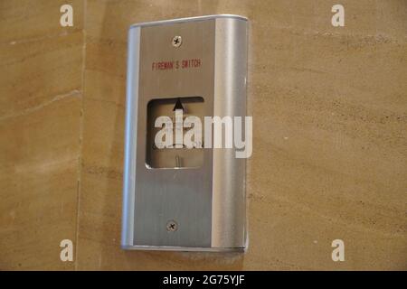Closeup of a sign stating "Fireman Switch" on a hotel lobby wall and a fire switch board. Fireman lift switch with beautiful background. Stock Photo
