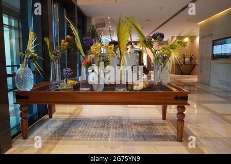 Beautifully arranged flowers in flower glass pots on the table. Elegant flowers arrangement in vases in hotel lobby. Flower, leaves arrangement on dis Stock Photo