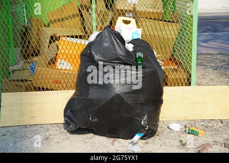 Dubai UAE December 2019 - Solo overflowing bag of black garbage trash bag kept outside. Mcdonalds and bottle coming out of torn black trash bag. Big c Stock Photo