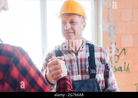 Senior male builder shaking hands with his colleague Stock Photo