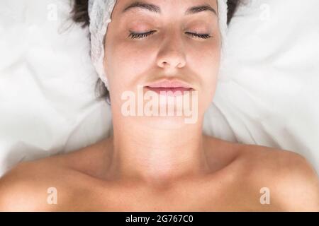 Young woman laying eyes closed, getting facial beauty treatment, view from above. High quality photo Stock Photo