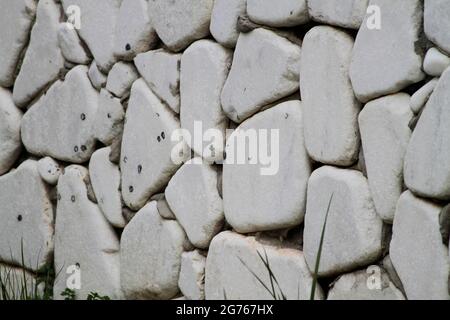 Wall cladding made using white, rounded white stones and grass. Wall cladding made using rounded stones. Stock Photo