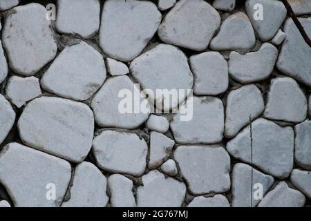 Wall cladding made using white, rounded white stones and grass. Wall cladding made using rounded stones. Stock Photo