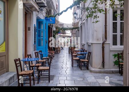 Syros island, Cyclades, Greece. May 26, 2021. Traditional open empty cafe with tables, chairs at cobblestone street of Ermoupolis capital of Siros or Stock Photo