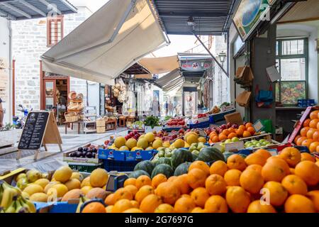 Syros island, Cyclades, Greece. May 27, 2021. Fruit markets local products shops with tent cafe at cobblestone street of Ermoupolis capital of Siros, Stock Photo