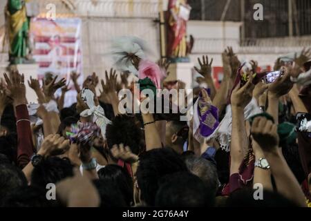 Filipino Catholic devotees raise miniature replicas of the Black Nazarene in Manila. A mammoth crowd of mostly barefoot Filipino Catholics prayed for peace in the increasingly volatile Middle East at the start of an annual procession of a centuries-old black statue of Jesus Christ in one of Asia's biggest religious events. Philippines. Stock Photo