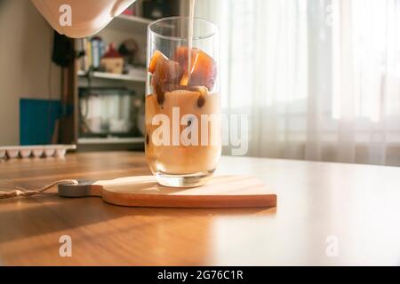 Making a refreshing drink by making ice cubes from coffee and pouring milk into a glass. A refreshing drink cold coffee on a summer morning. Stock Photo