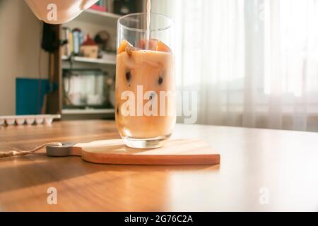 Making a refreshing drink by making ice cubes from coffee and pouring milk into a glass. A refreshing drink cold coffee on a summer morning. Stock Photo