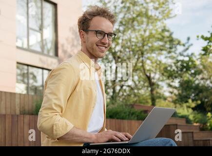 Handsome smiling businessman wearing eyeglasses using laptop computer, planning start up working from home. Successful business and career Stock Photo