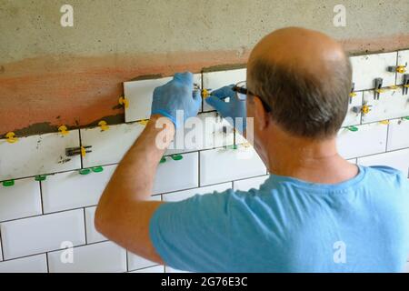 Worker putting tiles on the wall in the kitchen. Stock Photo