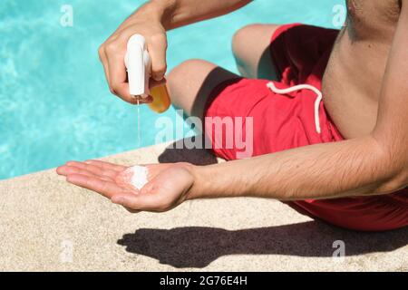 Young blonde woman rubbing sunscreen onto back of young man nest