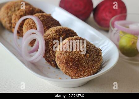 Air fried beetroot cutlets. Served with onions. Shot on white background Stock Photo