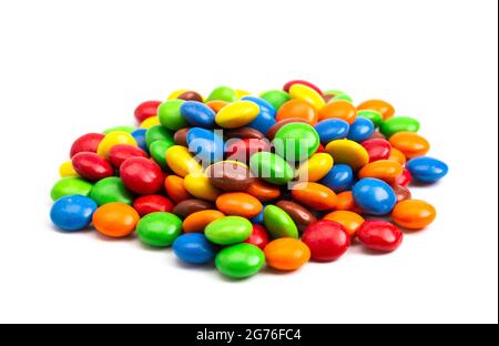 A Pile of Rainbow Colored Candy Coated Chocolate Buttons Isolated on a White Background Stock Photo