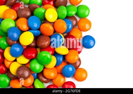 A Pile of Rainbow Colored Candy Coated Chocolate Buttons Isolated on a White Background Stock Photo