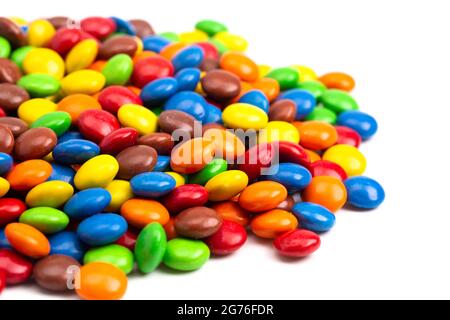A Pile of Rainbow Colored Candy Coated Chocolate Buttons Isolated on a White Background Stock Photo