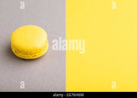 Yellow macaroon on trendy gray and yellow background. side view, copy space, close up, still life. Minimalism, morning, contrast concept. Stock Photo