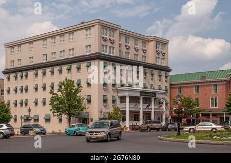 Gettysburg, PA, USA - June 14, 2008: Beige cubical Gettysburg hotel building at Lincoln Square roundabout under blue cloudscape with cars and green fo Stock Photo