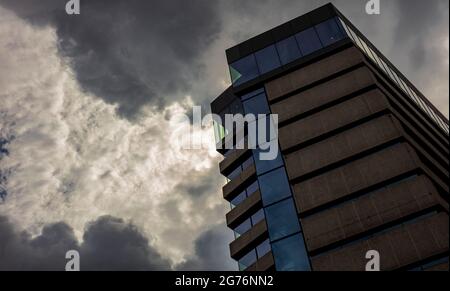Seventies building in Hammersmith, West London, UK against a dramatic dark cloudy sky Stock Photo