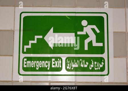 Emergency Fire Exit sign in corridor point way out of the building to escape in case of emergency, urgency and fire, Translated Arabic words ( exit in Stock Photo