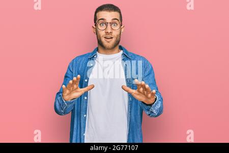 Young caucasian man wearing casual clothes afraid and terrified with fear expression stop gesture with hands, shouting in shock. panic concept. Stock Photo