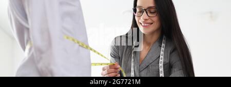 Woman designer takes measurements from client in an atelier Stock Photo
