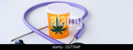 Jar of marijuana pills standing near stethoscope closeup Stock Photo