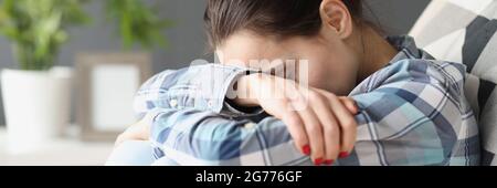 Sad woman sitting with her head bowed on sofa Stock Photo