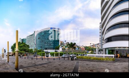 Puerto Santa Ana boulevard in Guayaquil, Ecuador. Many people walking along the malecon in front of the river. The Point and Wyndham Hotel. Stock Photo