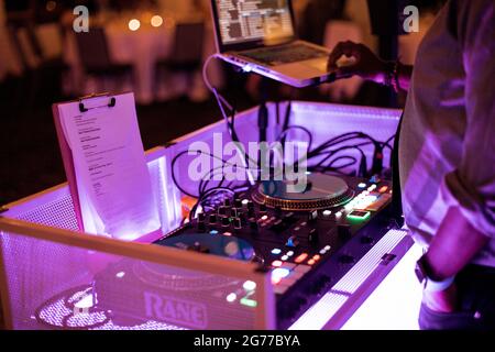 Close up of DJ console at the party. Neon lights over the hands of playing at wedding. Stock Photo