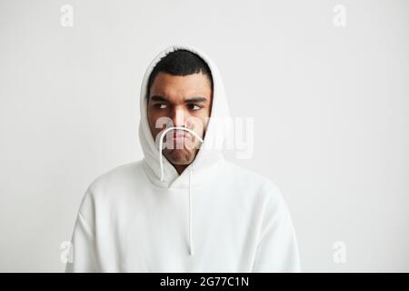 Minimal portrait of young man wearing hoodie and making faces, copy space Stock Photo