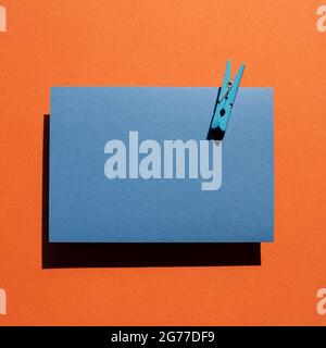 Blue memo pad with wooden clip on red background. top view, copy space Stock Photo
