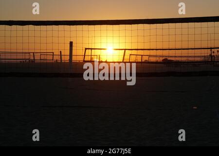 The sun sets on a southern California beach and highlights the beach volleyball courts. Stock Photo