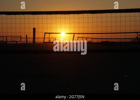 The sun sets on a southern California beach and highlights the beach volleyball courts. Stock Photo