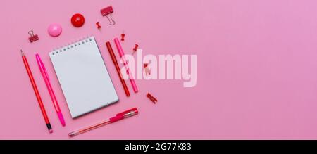 Markers of different pink shades with white notepad on pink background, top view. Pens and pencils are laid out around the notebook close-up Stock Photo