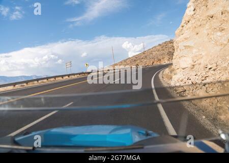 Driving on a curved uphill road beside a rocky mountain in Hurricane, Utah Stock Photo