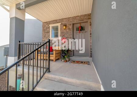 Outdoor stairs leading to porch and gray front door with wreath and glass pane Stock Photo