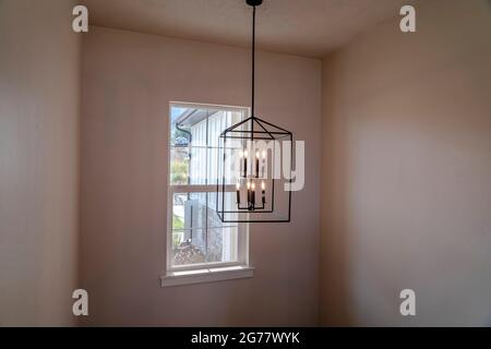 Chandelier with modern geometric design against small window inside a home Stock Photo
