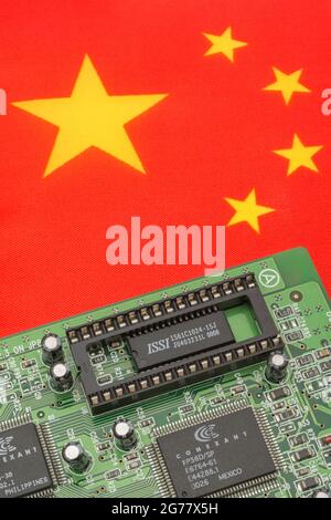 Chinese national flag with green PCB circuit board with empty EPROM socket. For 2021 integrated computer chip shortages, semiconductor shortages. Stock Photo