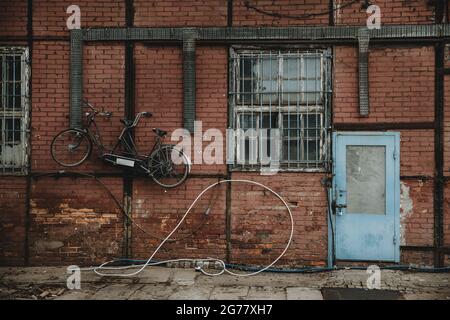 Blue door in red brick wall of half-timbered building with tandem bicycle hanging on the wall in docks of Gdansk Stock Photo