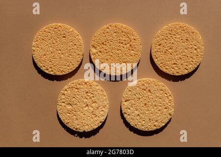 set of natural round cellulose sponges for face cleansing and make up remowal on brown background. Stock Photo