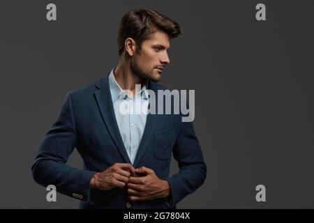 Profile of young beautiful focused european businessman. Front view of bearded man with dark hair wearing business jacket and looking at camera. Isola Stock Photo