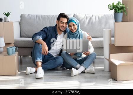 Loving arab family using laptop at new apartment Stock Photo