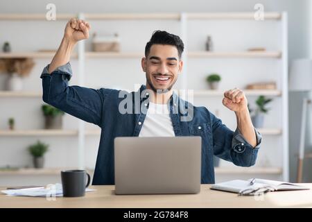 Emotional arab man freelancer celebrating successful business deal Stock Photo