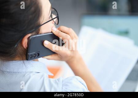 Businesswoman talking on smartphone and reading document solving corporate business problems Stock Photo