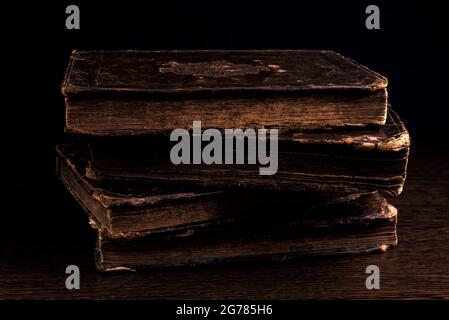 Stack of old worn shabby Jewish books in leather binding in the dark. Closeup. Selective focus. Low key Stock Photo