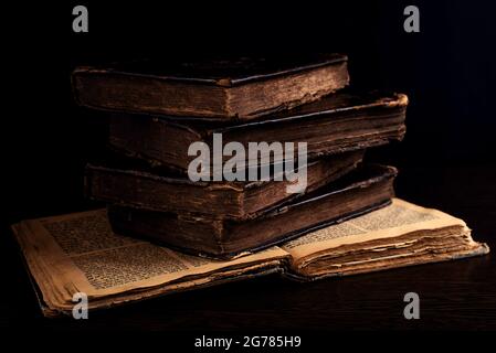 Stack of old worn shabby jewish books in leather binding on the open pages of Machzor in the dark. Closeup. Selective focus. Low key Stock Photo