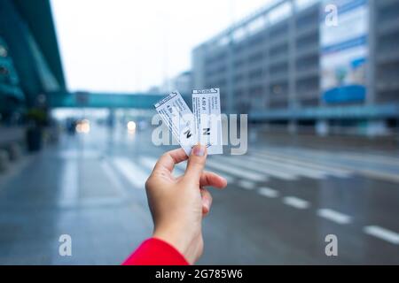 The girl holds in her hand two tickets for the bus traveling from the airport to the city. Stock Photo