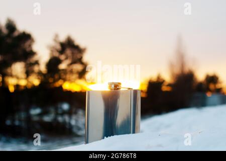 metal flask stands in the snow against the background of the sun Stock Photo